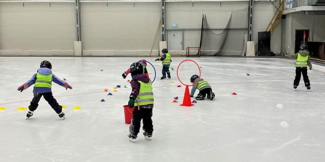 Barn som åker skridskor i ishall.