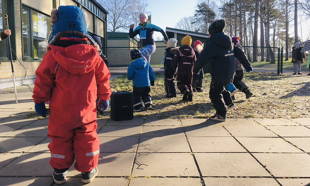 Barn och pedagog gymnastiserar på gården.