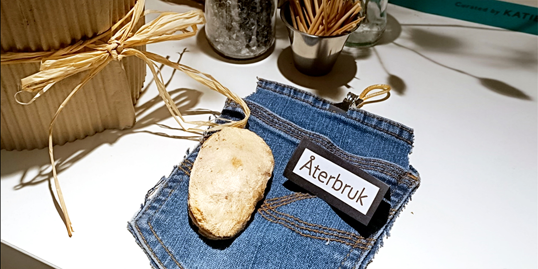 En avsprättad jeansficka, returpapp och en liten skylt med texten Återbruk.