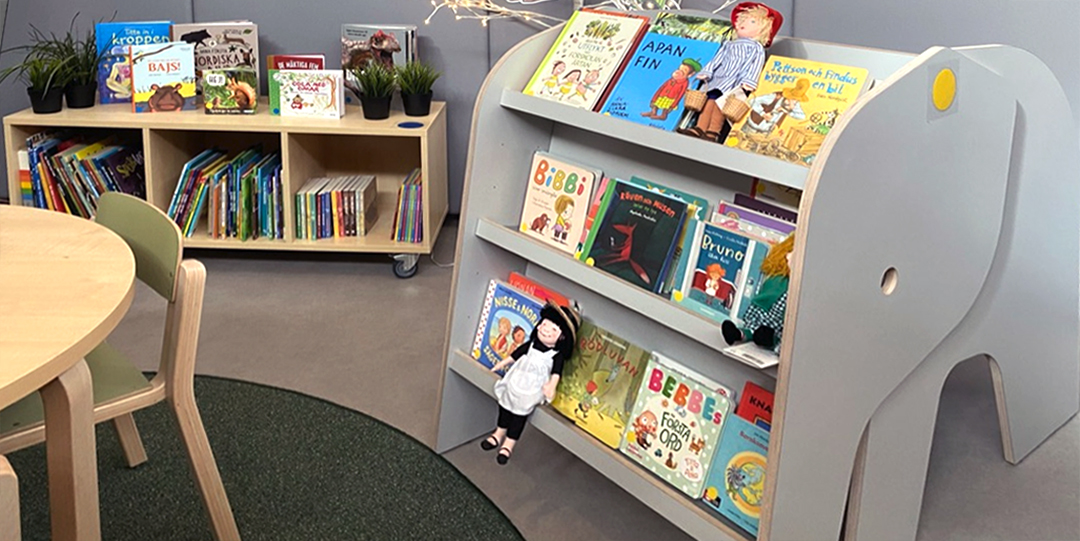 Förskolebibliotek med bokhyllor och böcker.