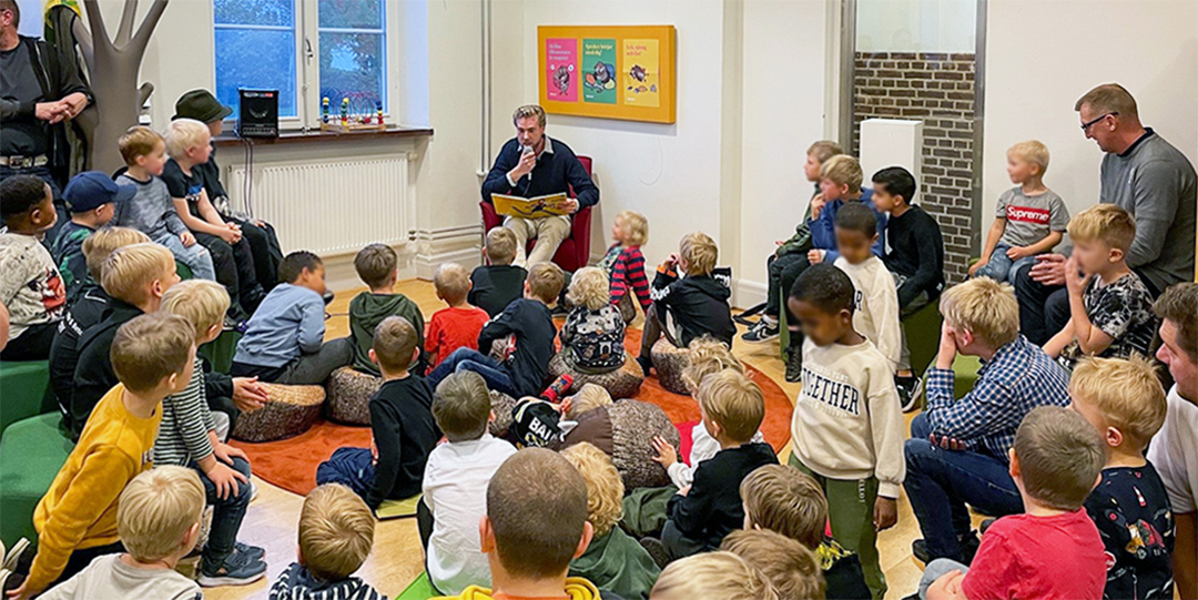 Högläsning för stor grupp barn på biblioteket.