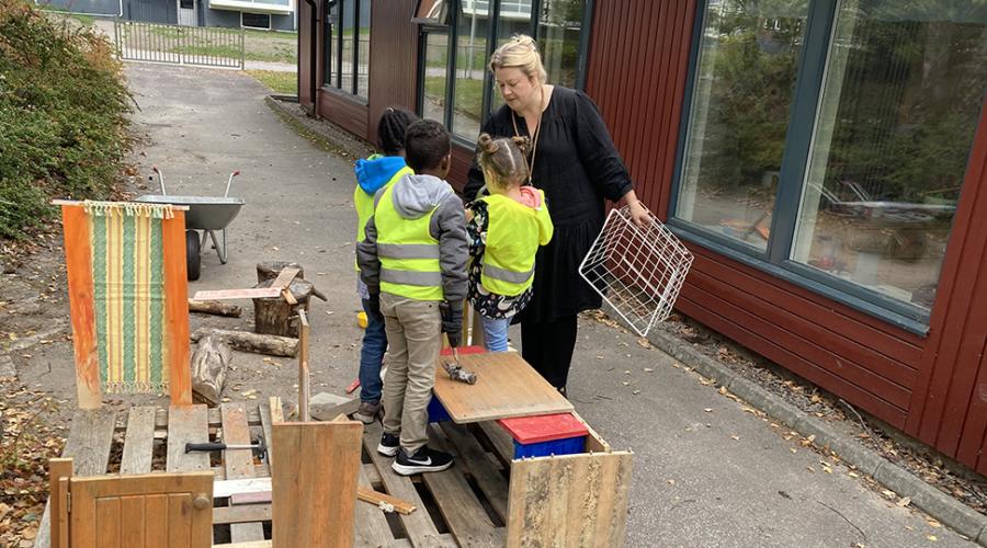 Barnen bygger ett hus tillsammans i snickeristationen på förskolegården.