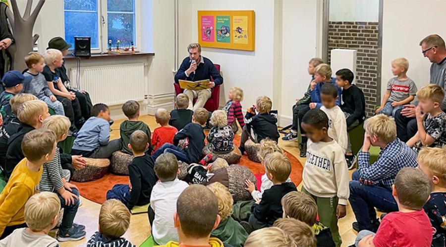 Högläsning för stor grupp barn på biblioteket.