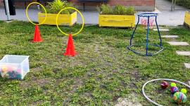Bollar, rockring och andra aktiverande föremål på en gräsmatta utanför förskolan.